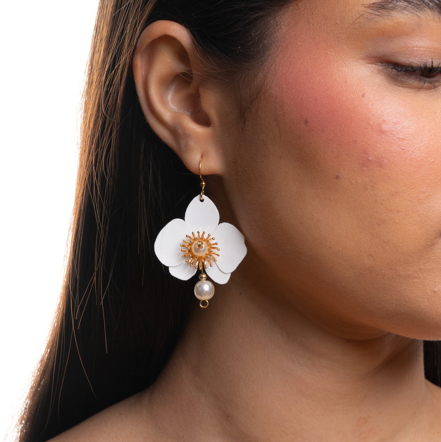 Close-up of a woman wearing a floral earring with a pearl accent.